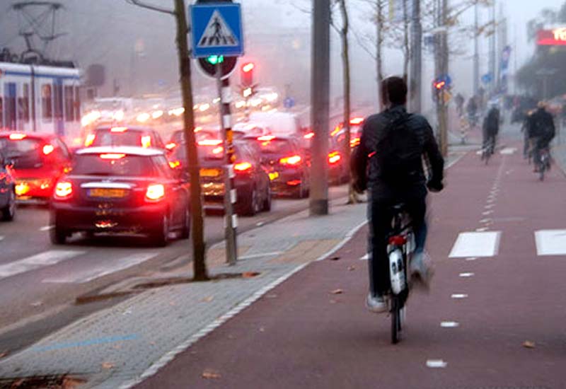 Prawdziwy Amsterdamczyk przejeżdża skrzyżowanie na rowerze przy czerwonym świetle